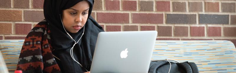 Female student with hijab looking at laptop
